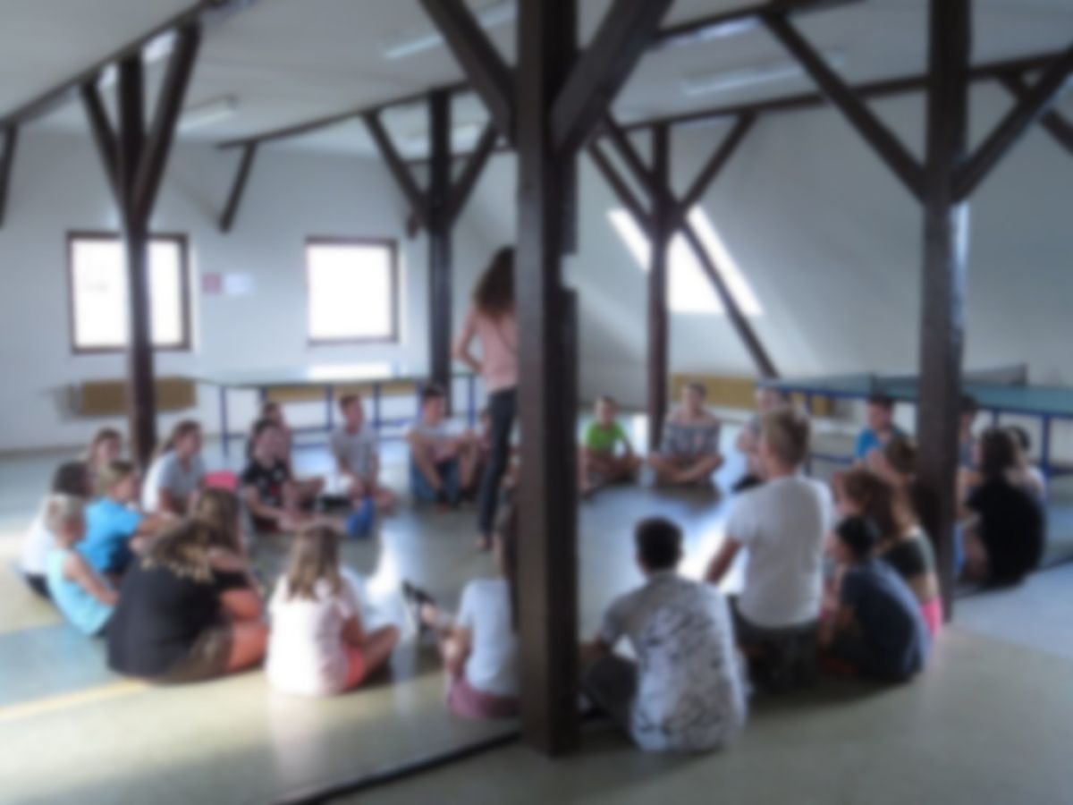 Ministranten sitzen während eines Spiels in einem Kreis auf dem Boden