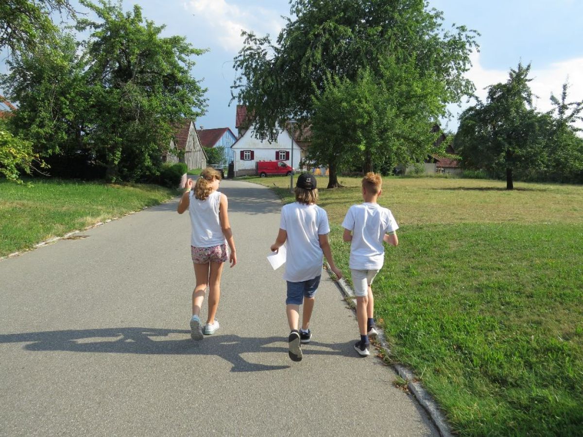3 Ministranten während einer Schnitzeljagd auf einem Weg im Grünen